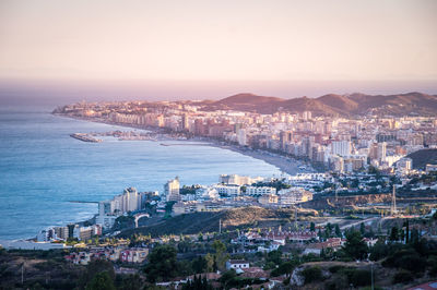 High angle view of city by sea against clear sky during sunset