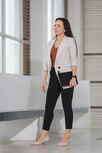 Full length of woman standing against wall