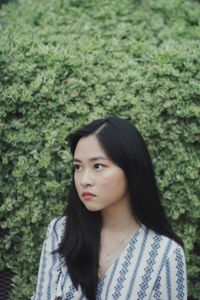 Thoughtful young woman against trees at park