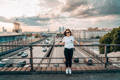 Full length of man standing on bridge in city against sky