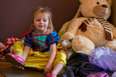 Happy cute girl sitting by stuffed toy at home