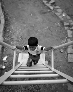 High angle view of boy moving up on ladder