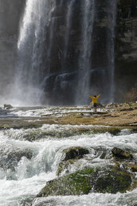 Man standing against scenic waterfall