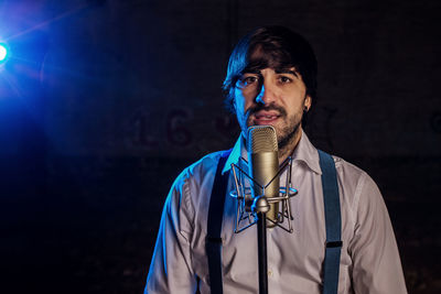 Man singing on microphone against black background