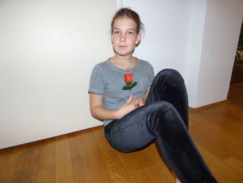 Portrait of boy sitting on hardwood floor at home