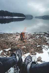 Low section of man at lakeshore during winter 