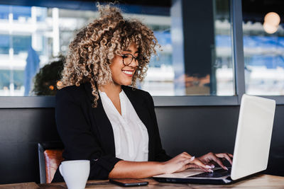 Young businesswoman using laptop at cafe