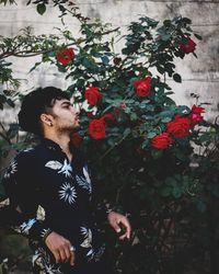 Full length of young man standing by flowering plants