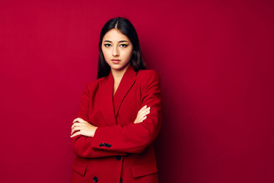 Portrait of young woman standing against yellow background