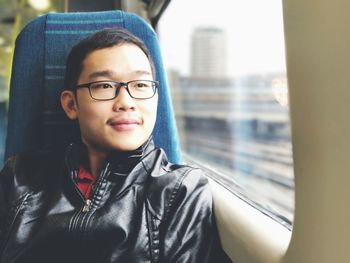 Close-up of young man looking through window while traveling in train