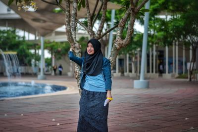 Portrait of woman standing by tree