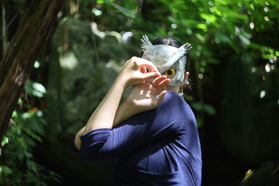 Midsection of woman holding ice cream against trees