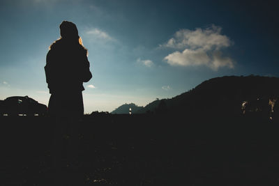 Silhouette man standing on mountain against sky