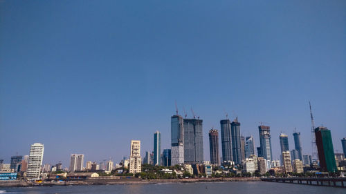 Modern buildings in city against clear blue sky