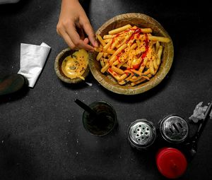 Cropped image of person holding french fries served in bowl