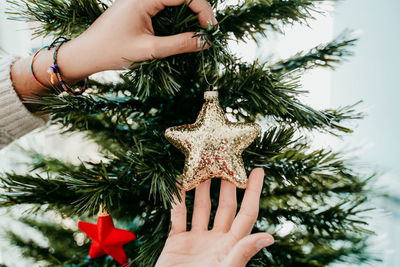 Close-up of woman decorating christmas tree at home