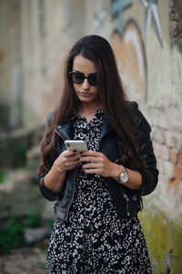 Attractive young woman looking at her phone outside and walking