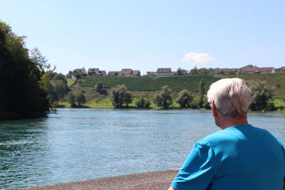 Rear view of woman looking at lake against sky