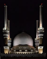 High section of illuminated mosque against sky at night