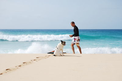 Man and dog on shore at beach against sky