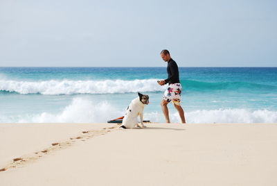 Friends on shore at beach against sky