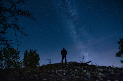 Rear view of silhouette man standing against star field at night