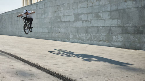 Man doing stunt with bmx bike in front of wall