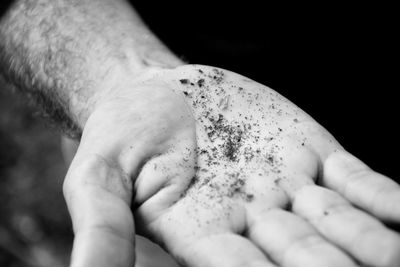 Close-up of person holding hands over black background