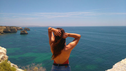 Midsection of woman at sea shore against sky