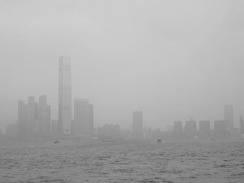 Modern cityscape by sea against sky