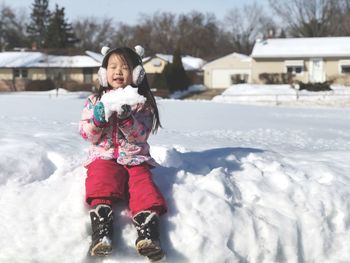 Full length of cute girl playing with snow during winter