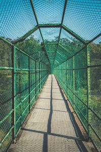 Diminishing perspective of covered bridge against sky