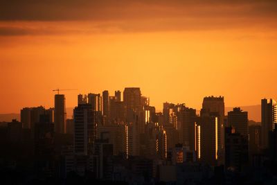 Modern buildings in city against sky during sunset