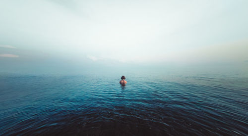 Rear view of man in sea against sky