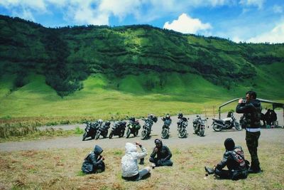 Group of people sitting on mountain against sky