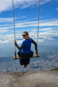 Full length of young woman on swing in playground