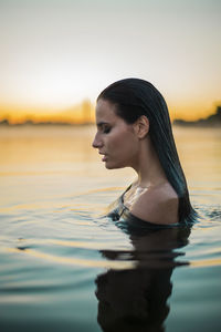 Side view of beautiful young woman in lake