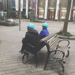 Father and son sitting on bench in city