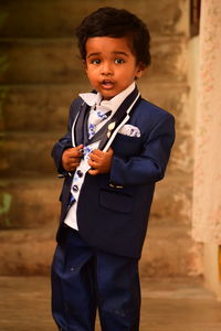 Portrait of boy in suit standing against steps