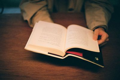 Midsection of person holding book on table