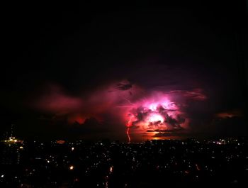 Illuminated cityscape against sky at night