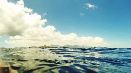 Surface level of calm sea against blue sky and clouds