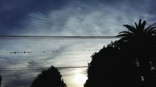 Low angle view of power lines against cloudy sky