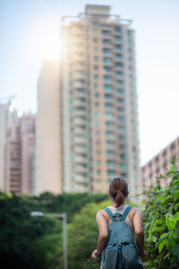 Rear view of woman against buildings in city