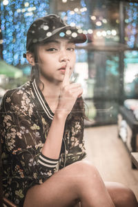 Portrait of woman with finger on lips seen through glass