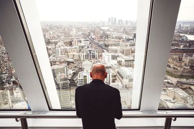 Rear view of man looking through window