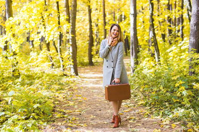 Full length of woman standing in park during autumn