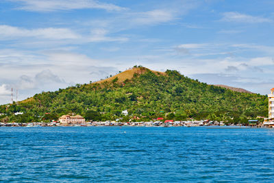 Scenic view of sea by mountain against sky