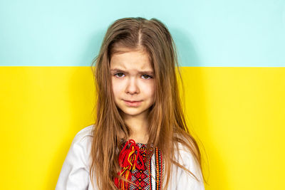 Portrait of young woman against yellow wall