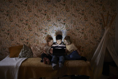 Boys using digital tablet on bed